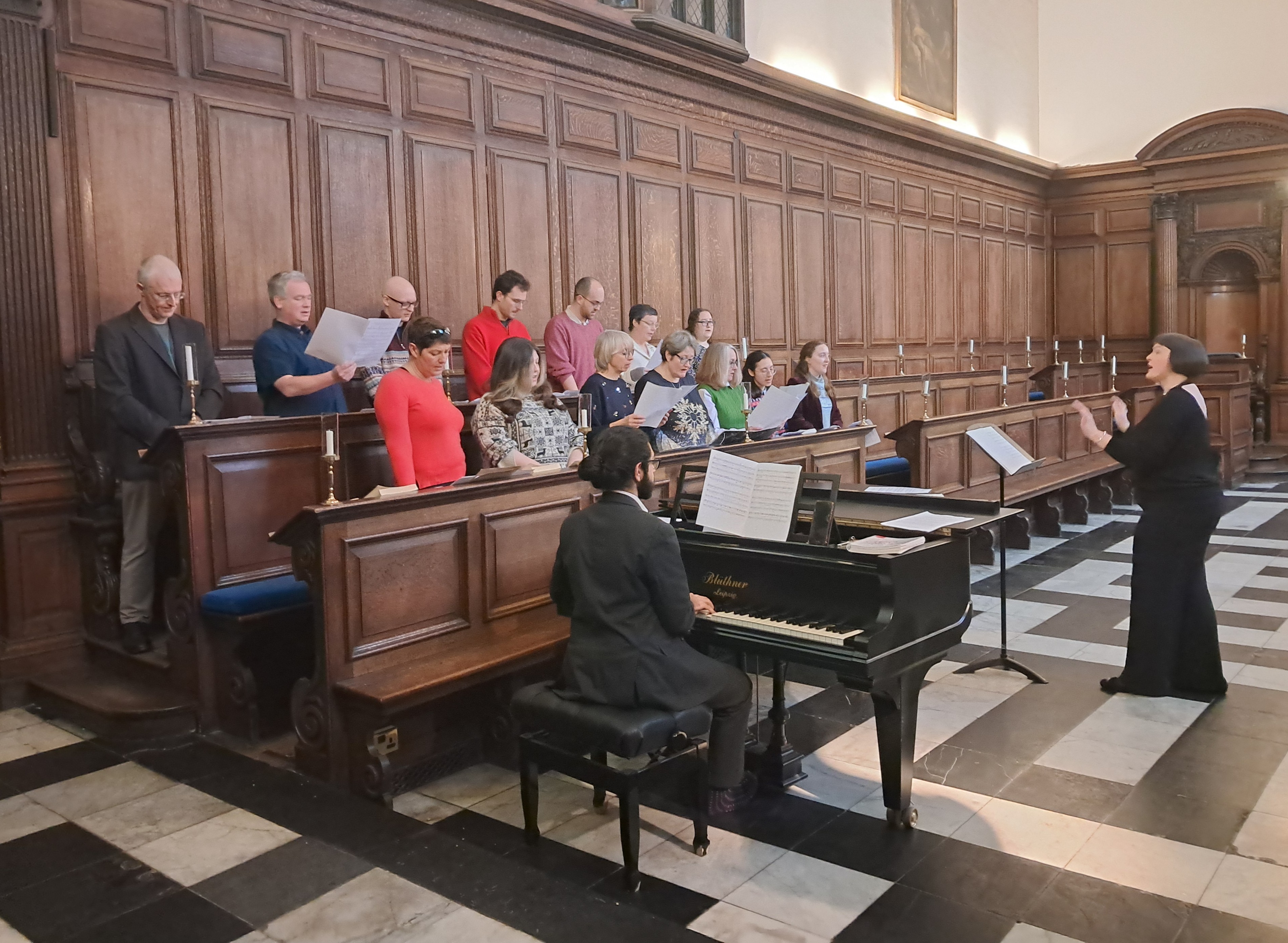 A group of people singing in Chapel with a pianist and piano in the foreground