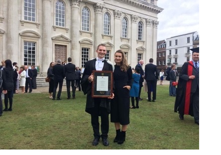 George, in academic gown and graduation hood, at his graduation ceremony at Senate House in Cambridge.