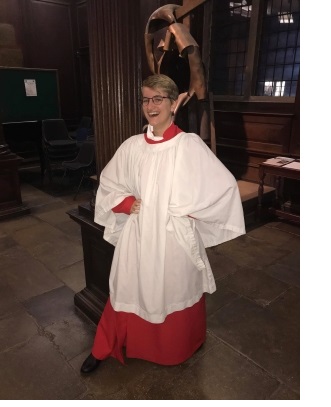 Alys in a red gown and white cassock, in the antechapel of Christ's College, Cambridge.