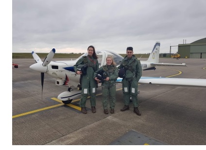 Hannah and two friends, in uniform, stood in front of a plane.