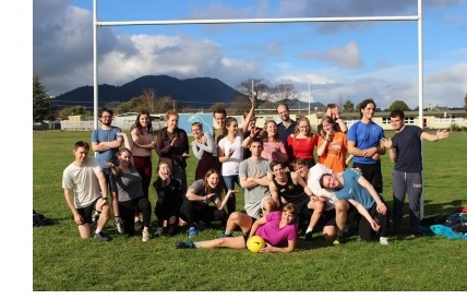 A large group of students (the Christ's College Choir) inside a goal on a football pitch.