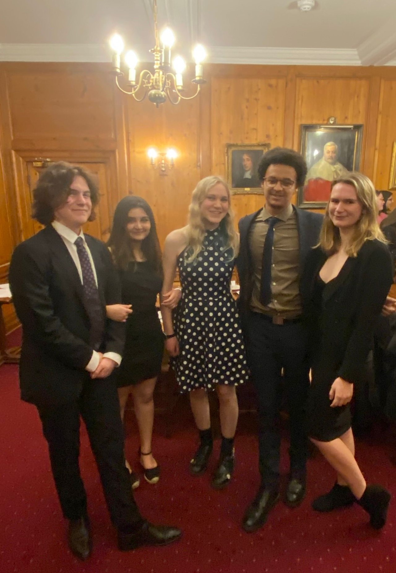 Five students in formal dress, in a line, under some fancy lighting