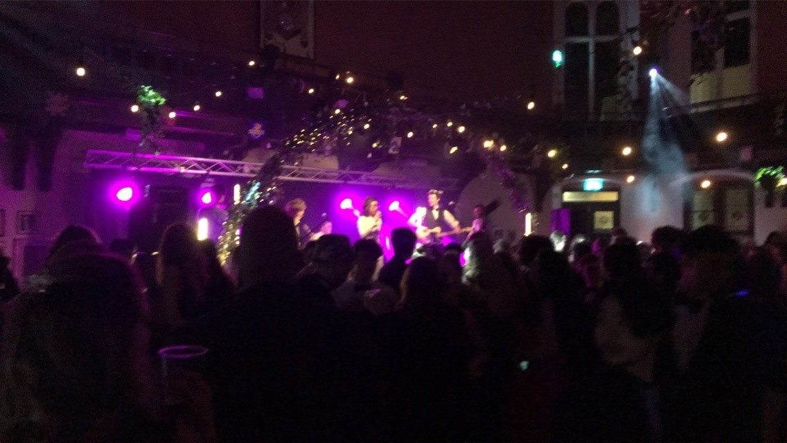 A stage with lights, musicians and people dancing