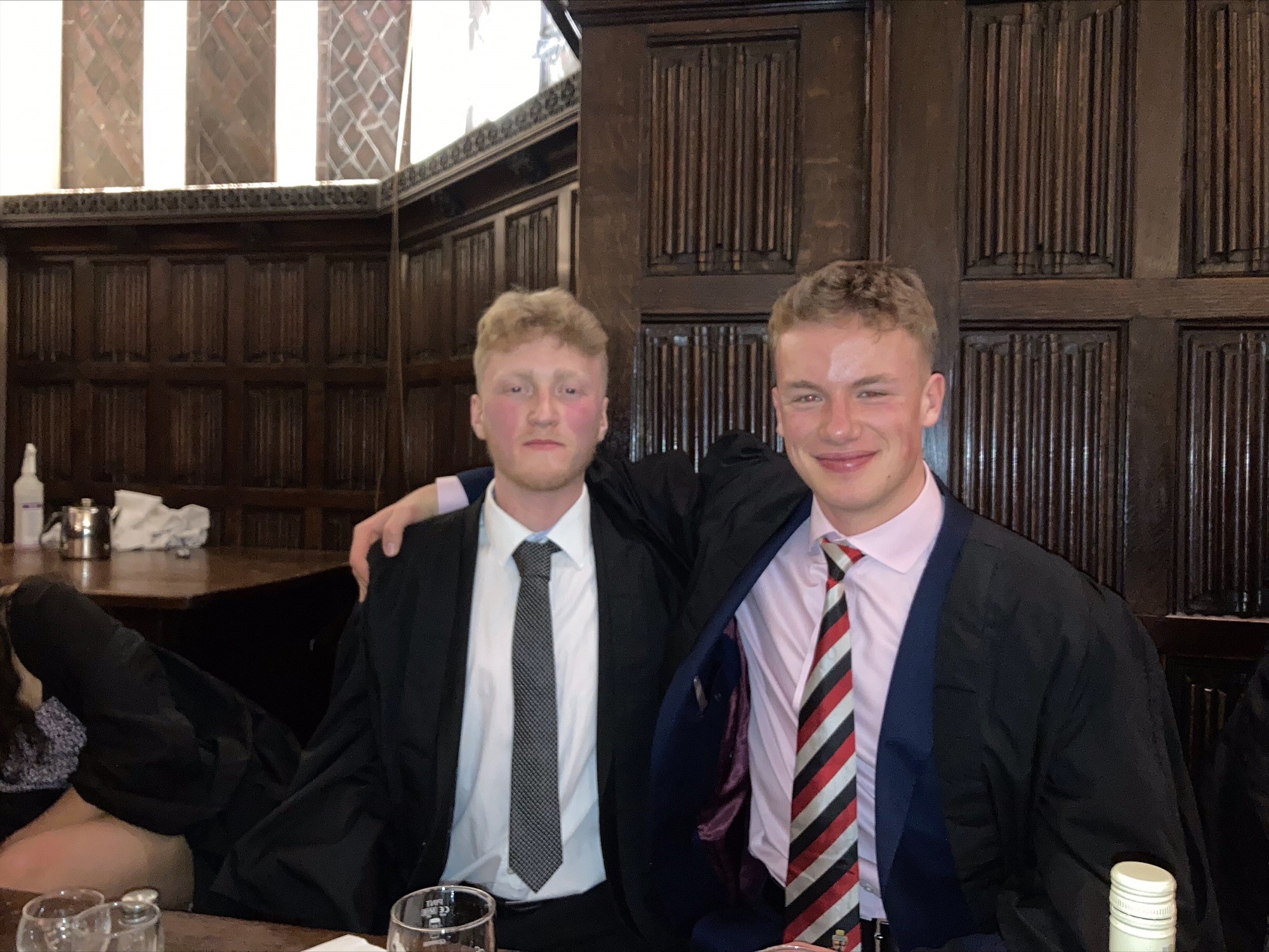 Two men in smart dress in a formal room, smiling at the camera