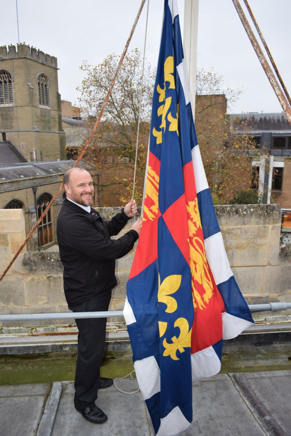 A porter raising the College flag