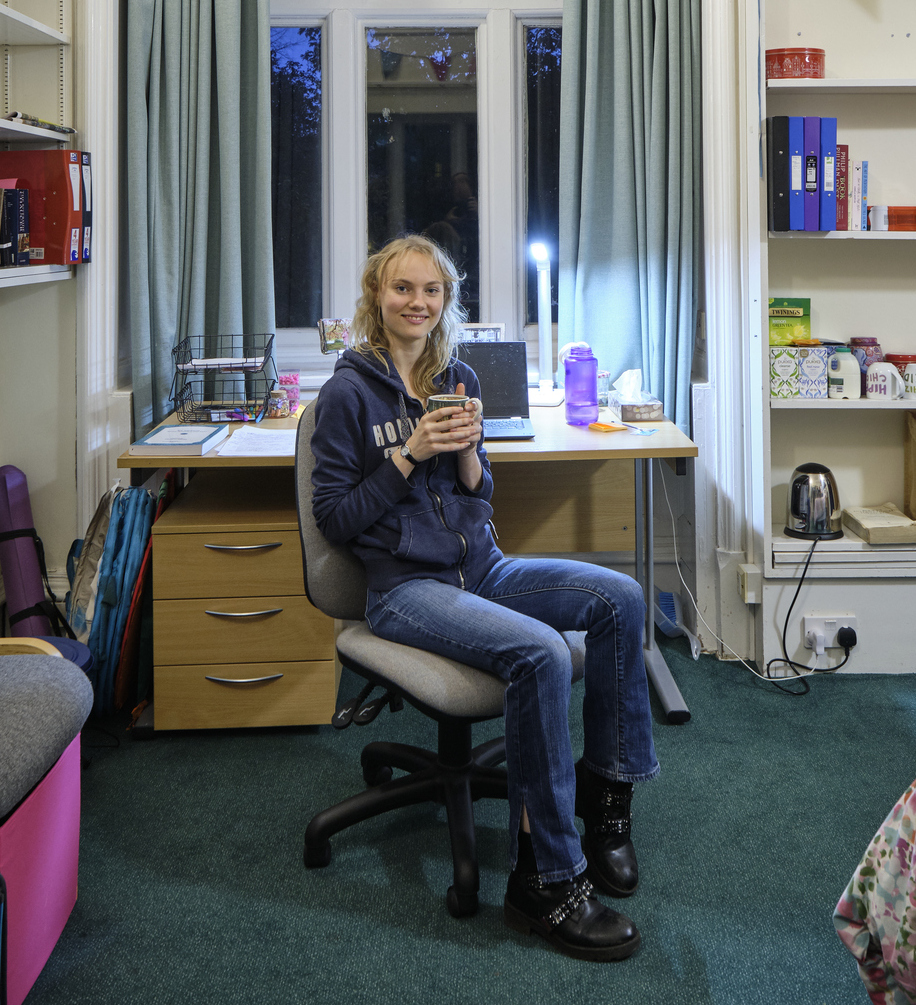 student in room with mug of tea