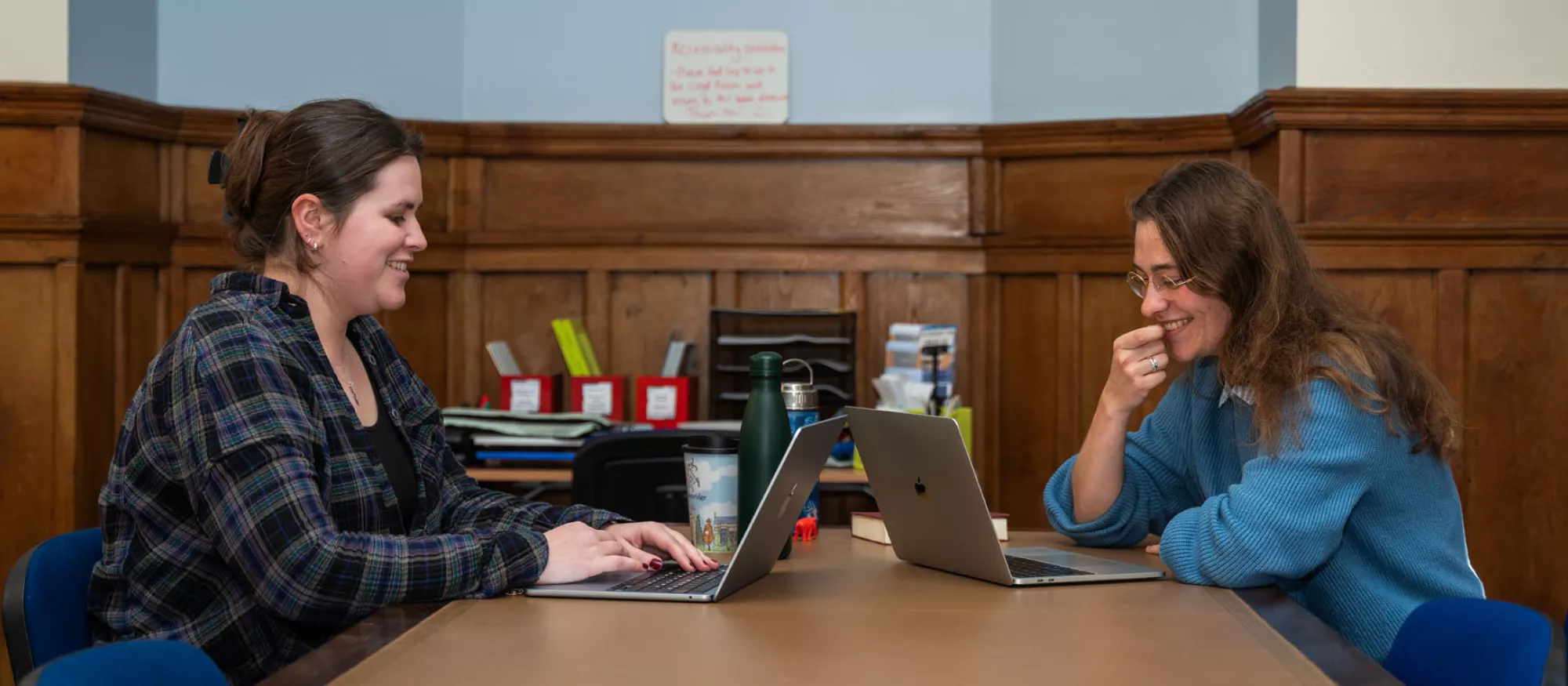 Two smiling students working on lap tops