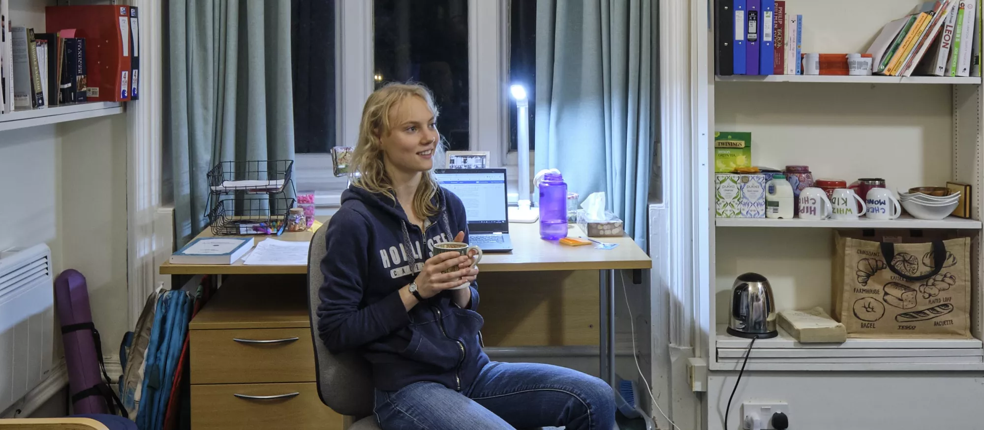 Student sitting in bedroom with cup of tea