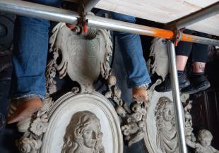 View of feet of conservators on scaffolding cleaning the monument