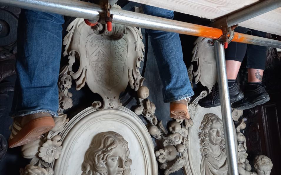 View of feet of conservators on scaffolding cleaning the monument
