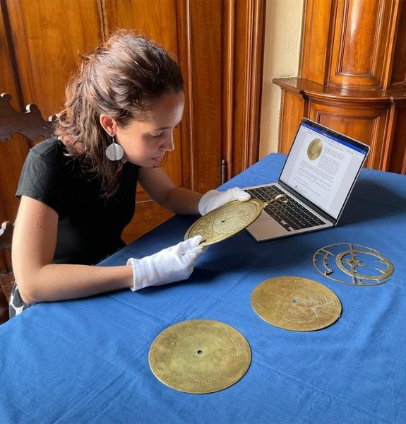 Person examining a brass instrument and with a laptop