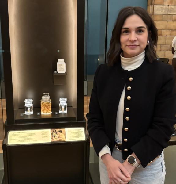 Marina beside a display case with three jars containing worms and a white medicine container