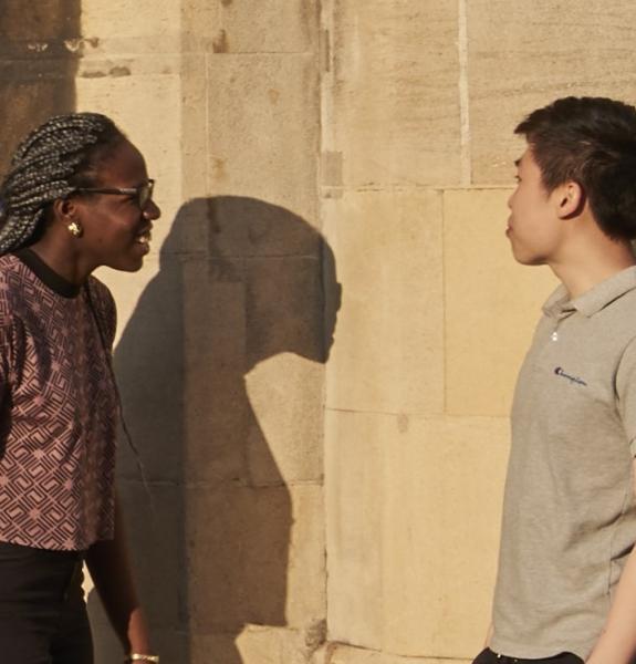 Two students talking by the main gate