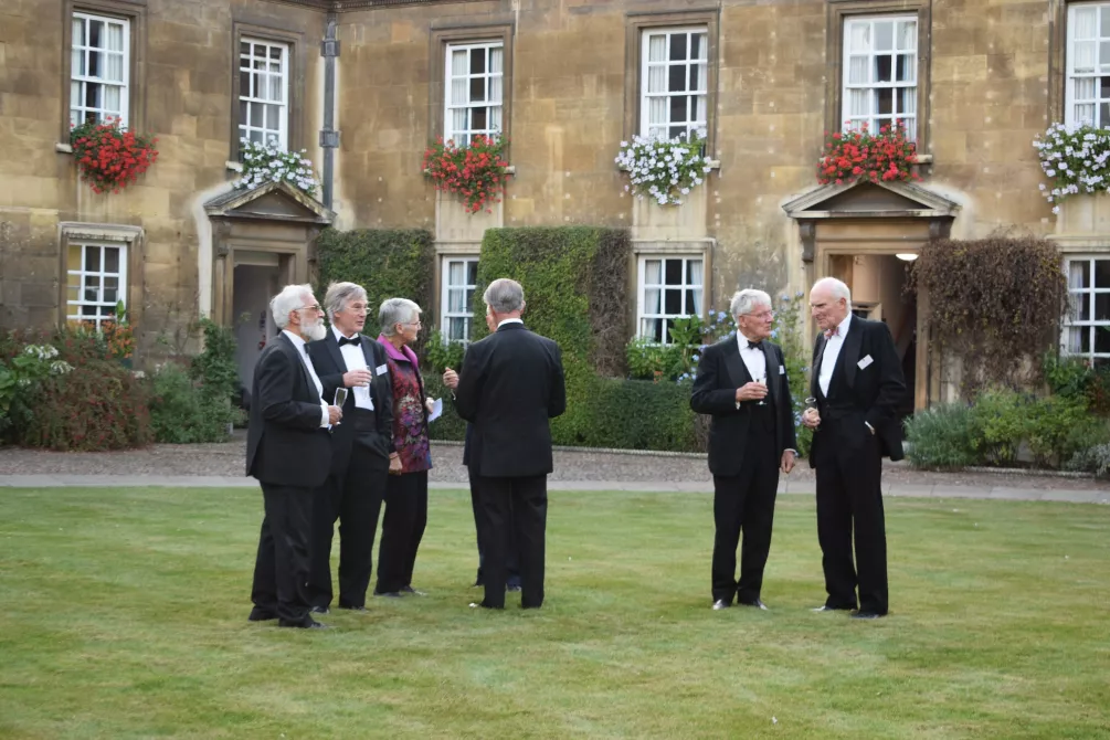 Men in formal dress gathered on college lawn 