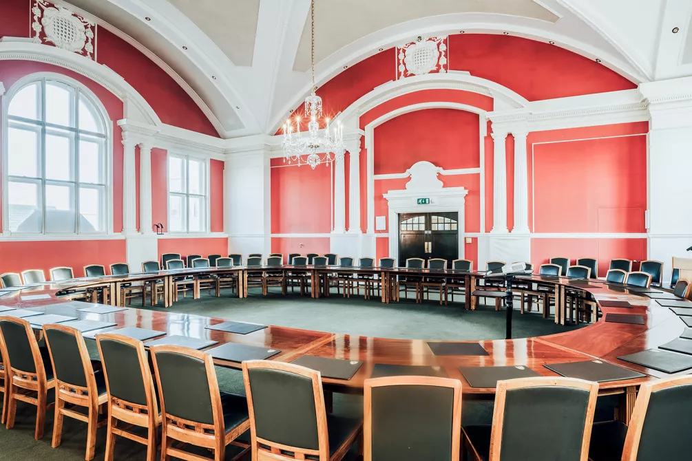 Christ's College Plumb Auditorium. A beautiful room for conferences and events featuring orange walls and unique hardwood table.