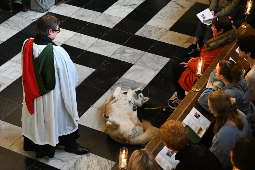 Chaplain robed with dog and congregation