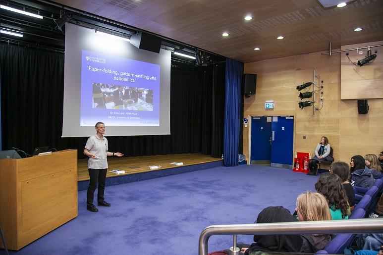 Lecturer in front of screen speaking to an audience